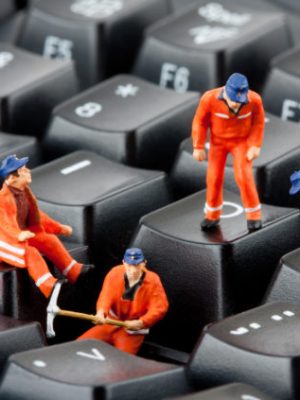 Small figurines of workers repairing computer keyboard