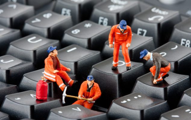 Small figurines of workers repairing computer keyboard